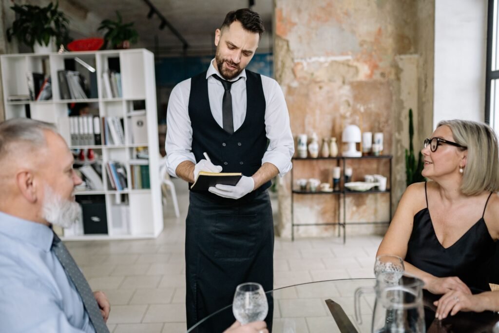 a woman and a man sit on a chait and a butler take a notes