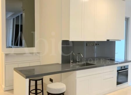 Dapur minimalis full furnished dengan kabinet putih, meja hitam elegan, dan dua stool bar bergaya simpel.