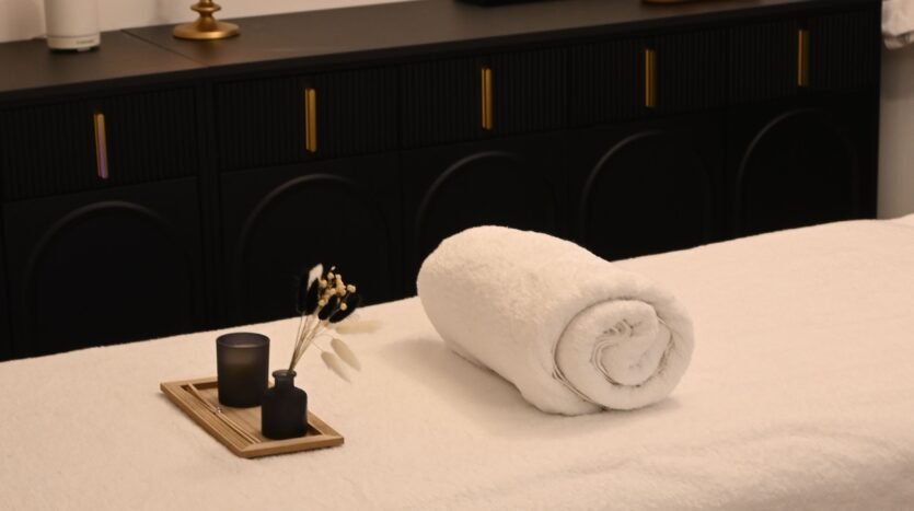 a towel and some fragrance on a bed
