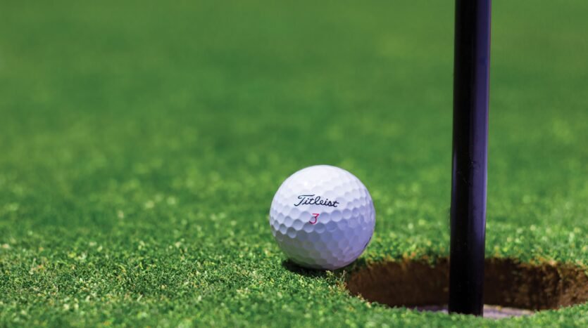 a golf ball near hole in a green golf course