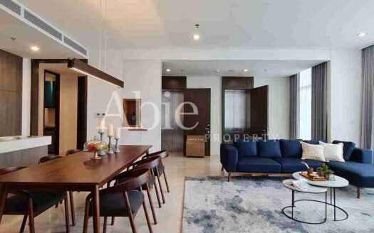 Ruang keluarga modern dengan sofa biru dan meja makan kayu di apartemen Verde Two