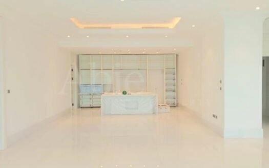 Ruang tengah luas dengan kitchen island dan pencahayaan elegan di apartemen St Regis Jakarta