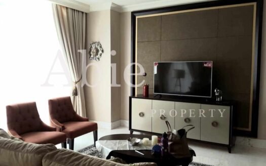 Ruang TV di unit Botanica 22702 dengan sofa nyaman, meja kopi, dan pencahayaan alami dari jendela besar.